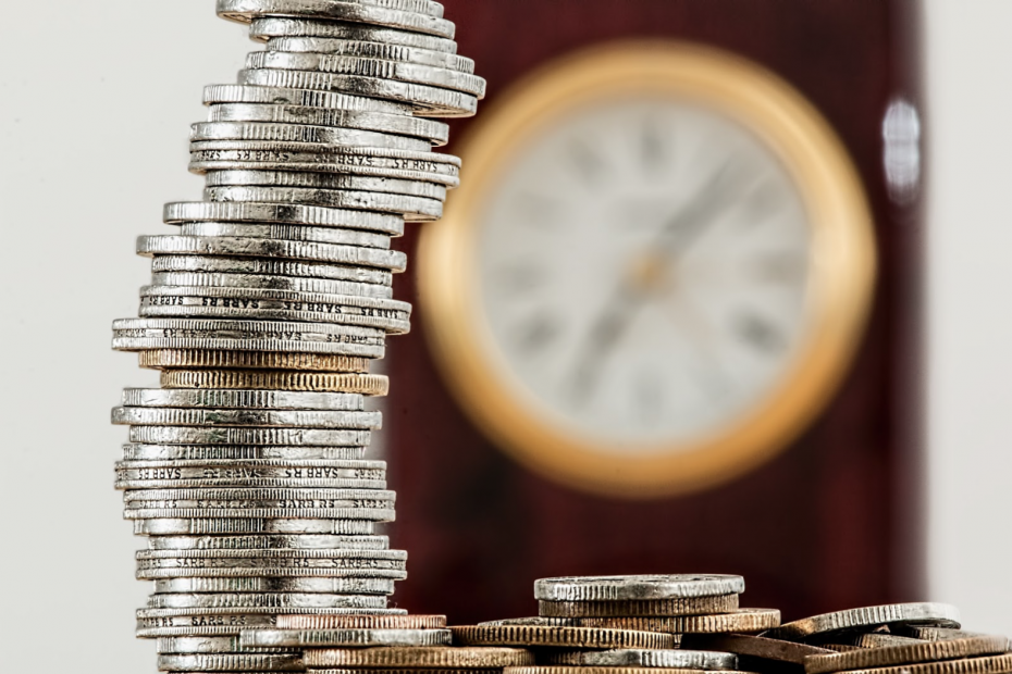 a stack of coins with a clock in the background