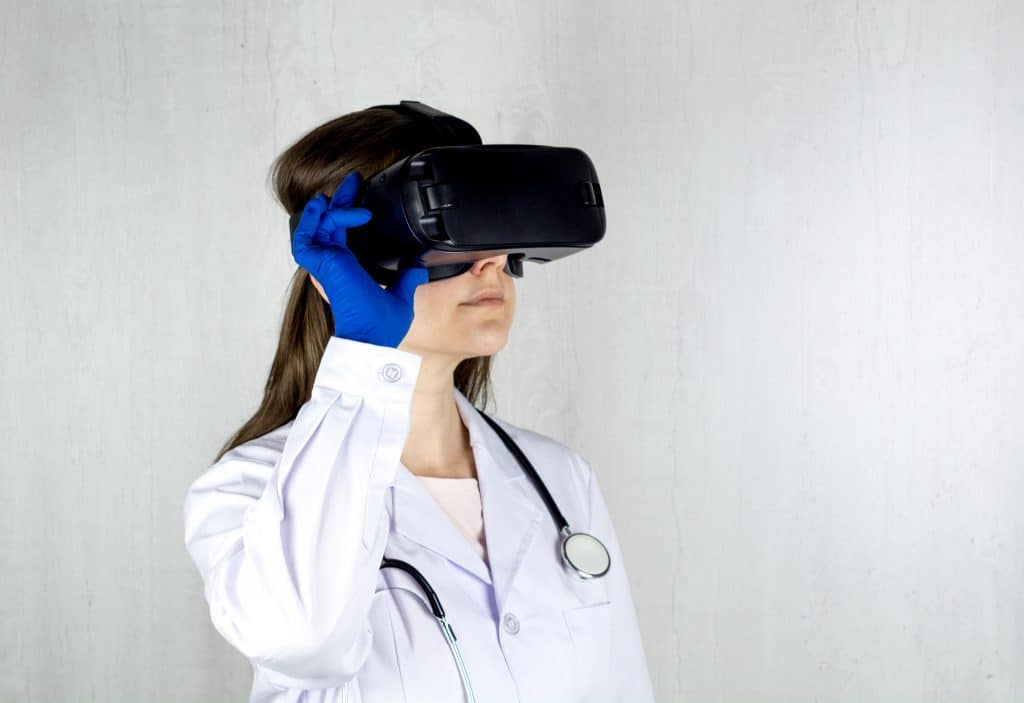 A woman in a coat wearing a stethoscope, VR headset and blue gloves
