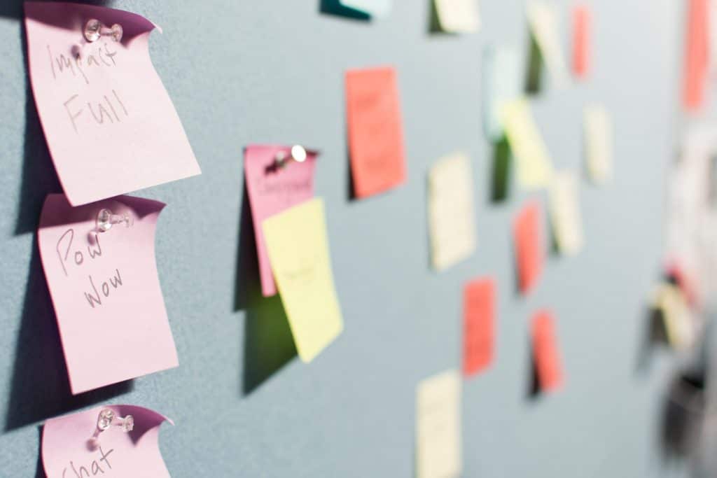 A board filled with different colored pinned sticky notes 