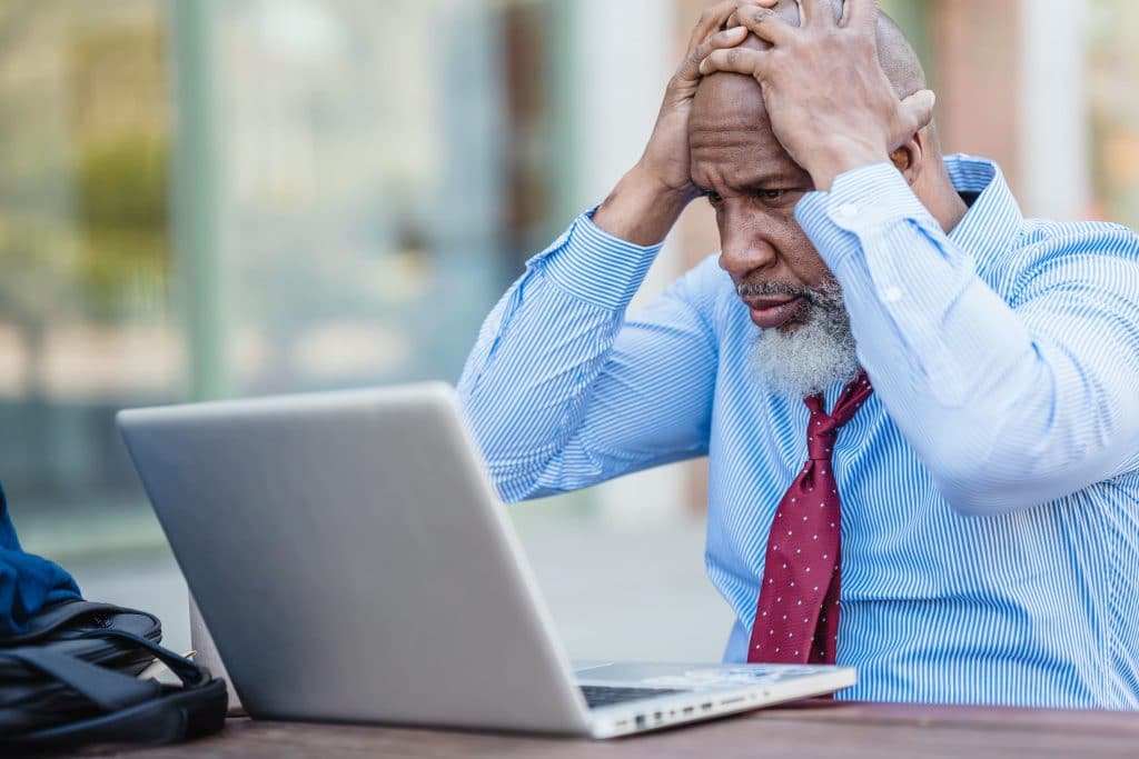 A man in disbelief holding his hands in his head while staring at the computer, representing the value of getting PPM documentation done right